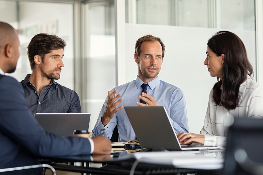 Four people in the office discussing ideas, with laptops open