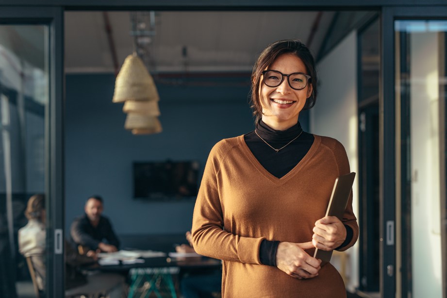 Smiling woman holding a tablet at office when managing her team