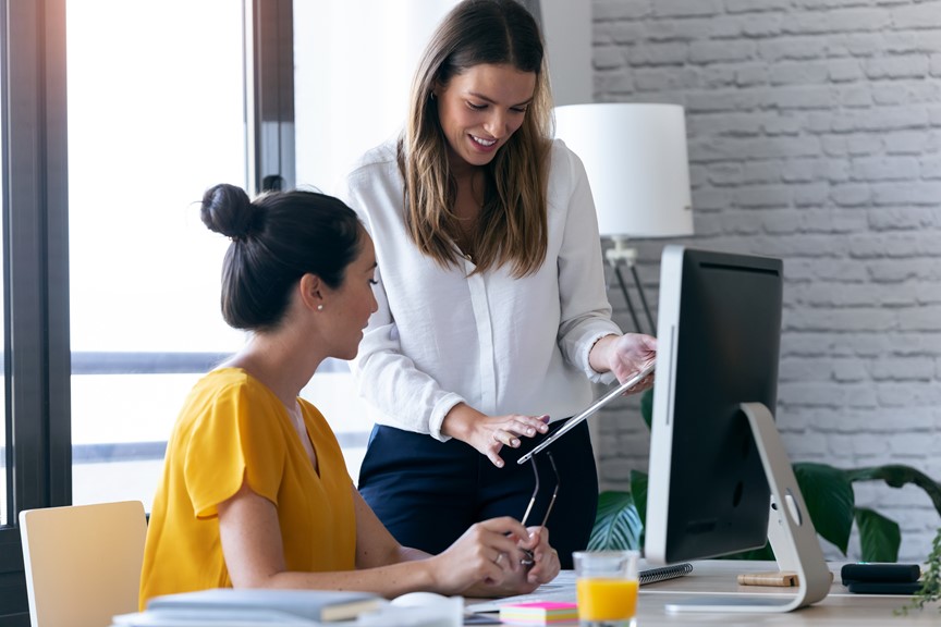 Two woman looking at the timesheet report in a portable device