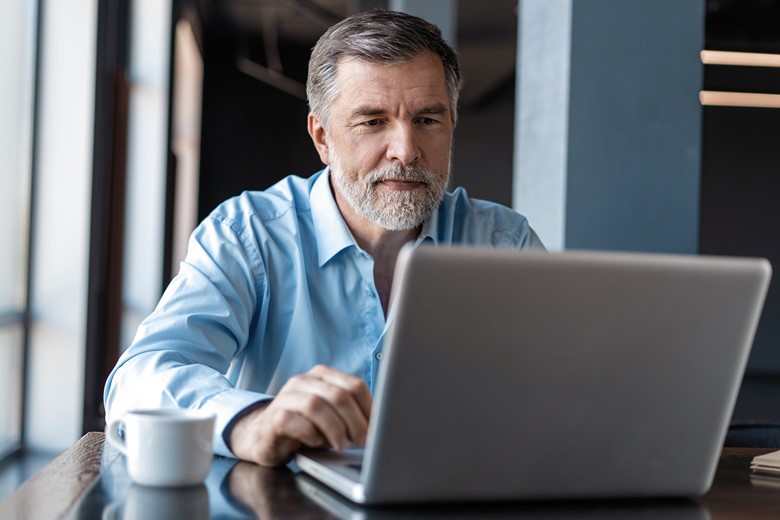 Mature businessman working in a laptop with coffee on the side