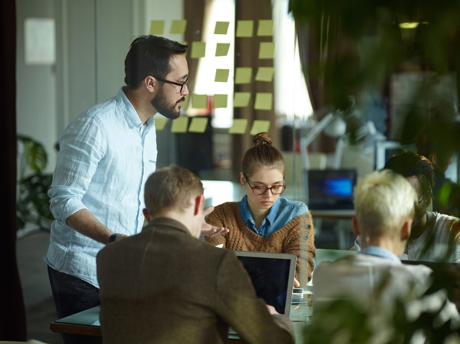 Man explaining his idea to the group of co-workers while collaborating in an office