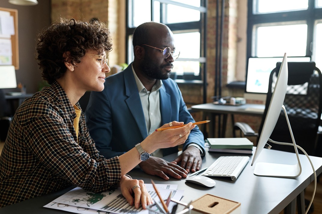 Group of multi-ethnic employees discussing at office using laptops and tablets