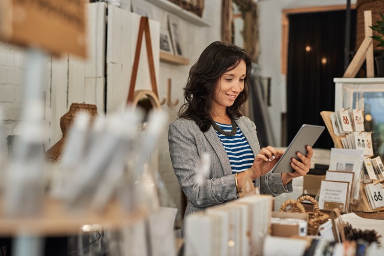 Small business owner approving timesheets of her employees with ease using a tablet