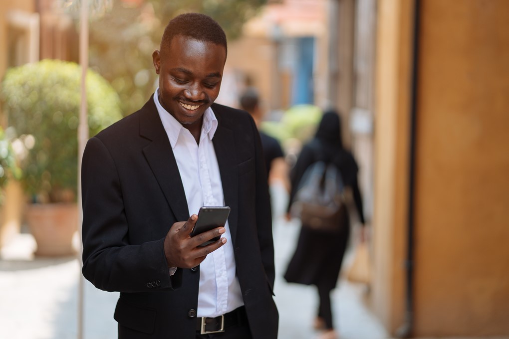 Smiling man using his smartphone to check time entry updates on the go