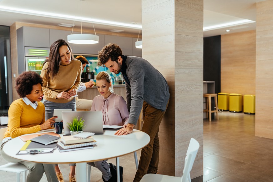 Four employees looking at the project and timesheet reporting in the laptop at the breakroom